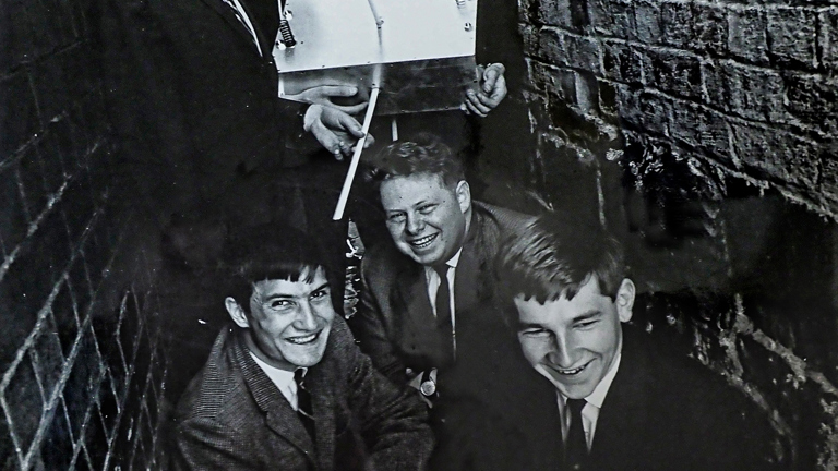 A group of young men in an alleyway holding a satellite. 